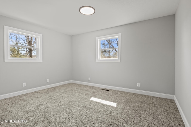 empty room featuring carpet floors, visible vents, and baseboards