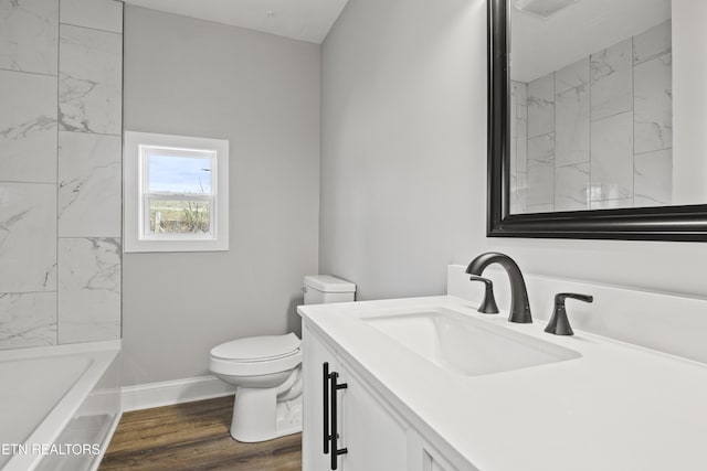 bathroom featuring toilet, baseboards, wood finished floors, and vanity