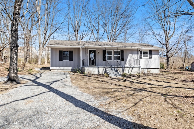 view of front of home with a shingled roof, covered porch, and driveway