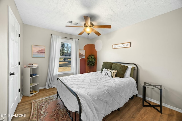 bedroom with a textured ceiling, ceiling fan, and hardwood / wood-style floors