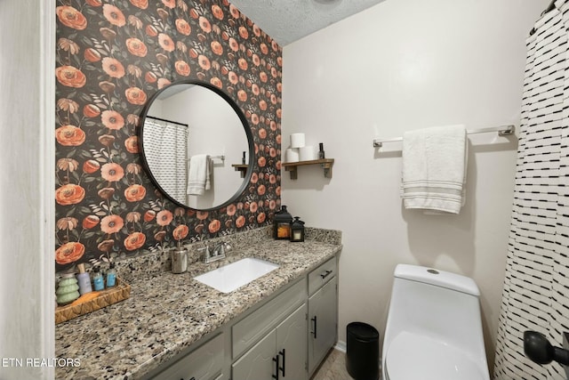 bathroom with a textured ceiling, toilet, and vanity