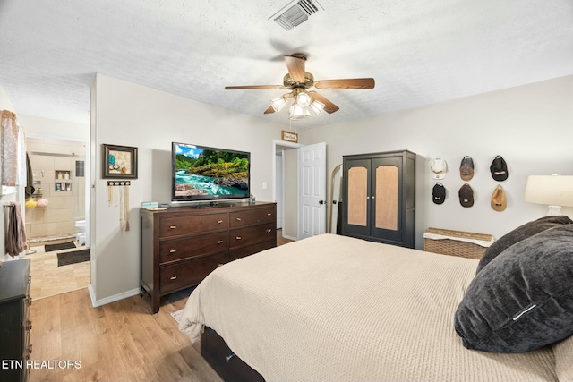 bedroom featuring light wood-type flooring, ceiling fan, ensuite bathroom, and a textured ceiling