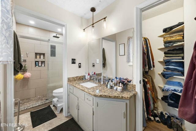 bathroom with tiled shower, vanity, and toilet