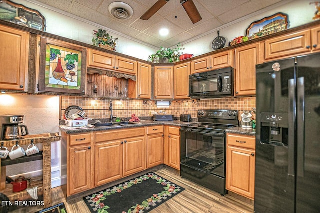 kitchen with sink, a paneled ceiling, light wood-type flooring, decorative backsplash, and black appliances