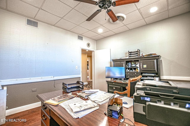 home office featuring a drop ceiling, dark wood-type flooring, and ceiling fan