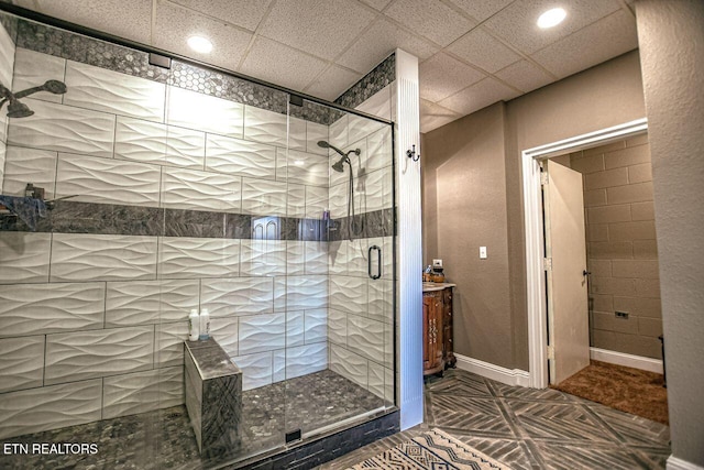 bathroom featuring a paneled ceiling and a shower with door