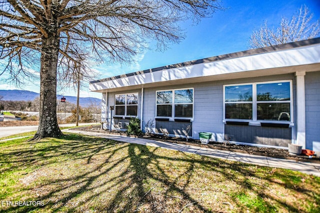 view of side of home with a mountain view and a yard