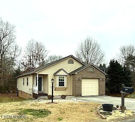 view of front of home featuring an attached garage, brick siding, driveway, crawl space, and a front lawn