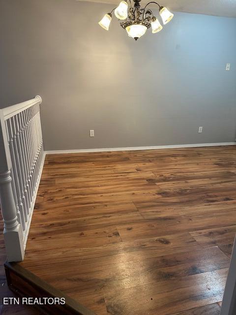 unfurnished room with a chandelier and dark hardwood / wood-style flooring