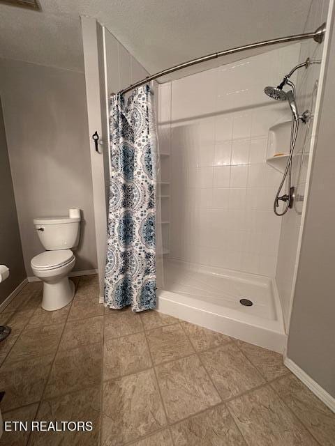 bathroom featuring a shower with curtain, toilet, and a textured ceiling