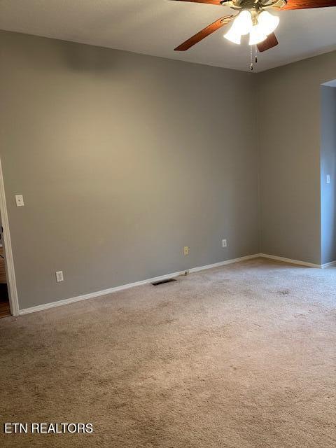 carpeted spare room featuring ceiling fan