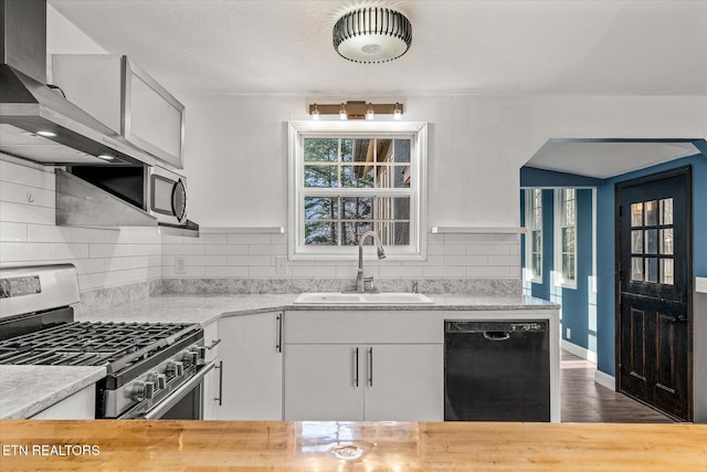 kitchen with butcher block counters, sink, white cabinetry, stainless steel appliances, and decorative backsplash