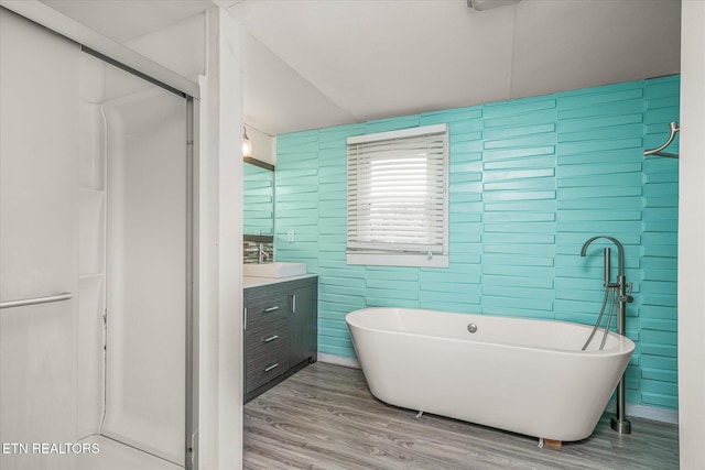 bathroom with independent shower and bath, vanity, wood-type flooring, and tile walls