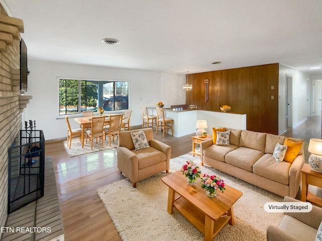 living room with a brick fireplace and light hardwood / wood-style flooring