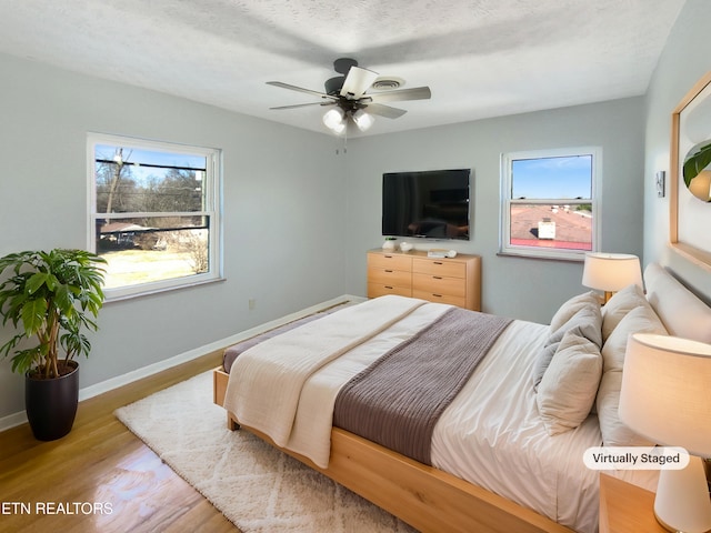 bedroom featuring ceiling fan, light hardwood / wood-style floors, and a textured ceiling