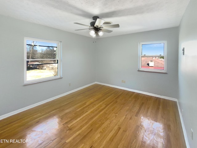 spare room featuring a textured ceiling, a healthy amount of sunlight, light hardwood / wood-style flooring, and ceiling fan