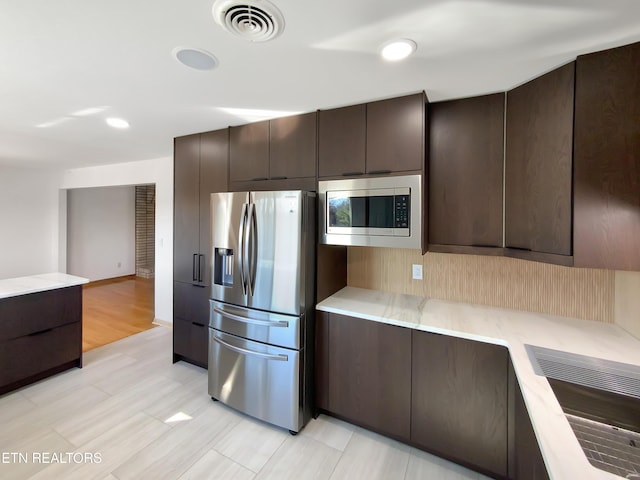 kitchen featuring dark brown cabinetry and appliances with stainless steel finishes