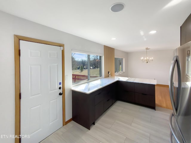 kitchen featuring a chandelier, stainless steel refrigerator, kitchen peninsula, and hanging light fixtures