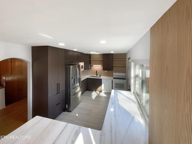 kitchen with sink, white appliances, and dark brown cabinetry