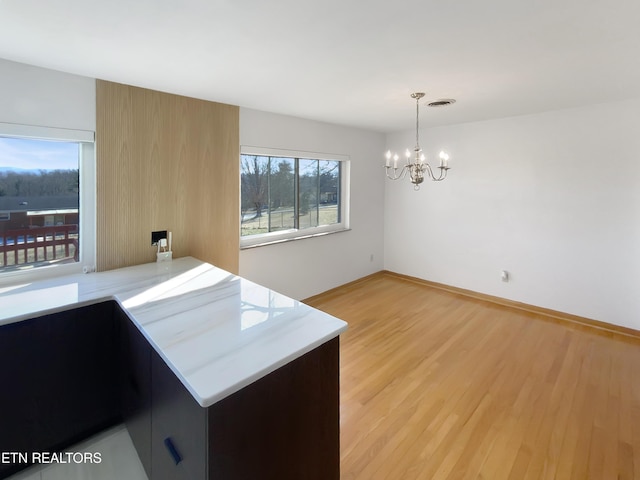 kitchen featuring kitchen peninsula, light hardwood / wood-style flooring, a wealth of natural light, and hanging light fixtures