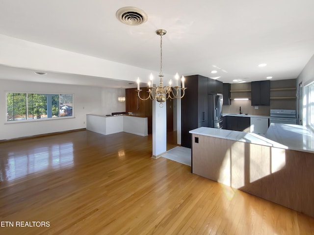 kitchen with white appliances, an inviting chandelier, and light hardwood / wood-style floors