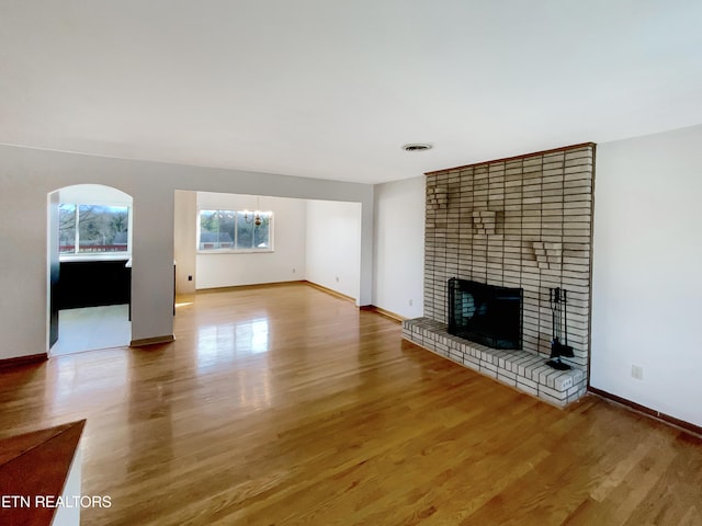 unfurnished living room featuring a notable chandelier, light hardwood / wood-style floors, and a fireplace