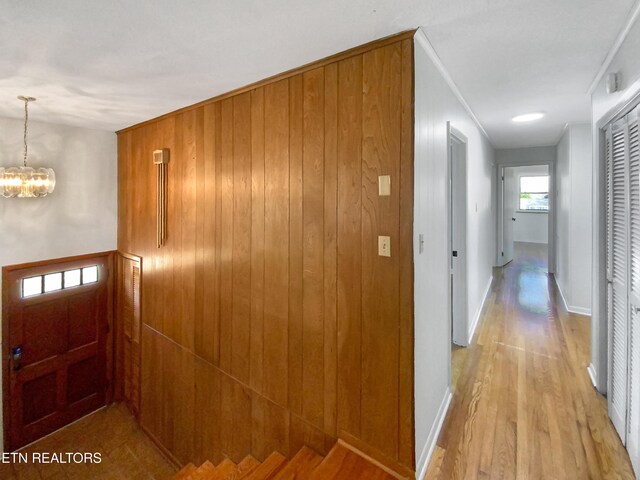 corridor with crown molding, light hardwood / wood-style flooring, and a notable chandelier