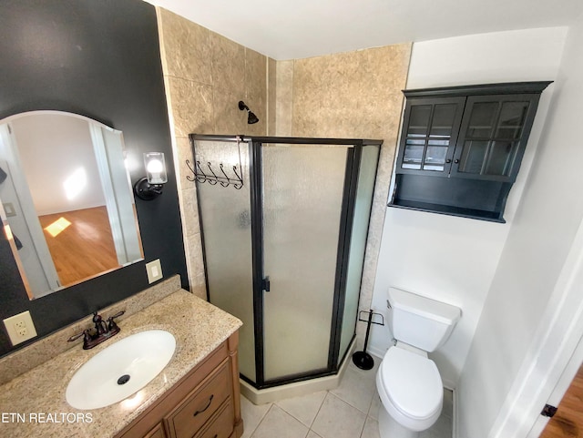 bathroom featuring vanity, toilet, a shower with door, and tile patterned flooring