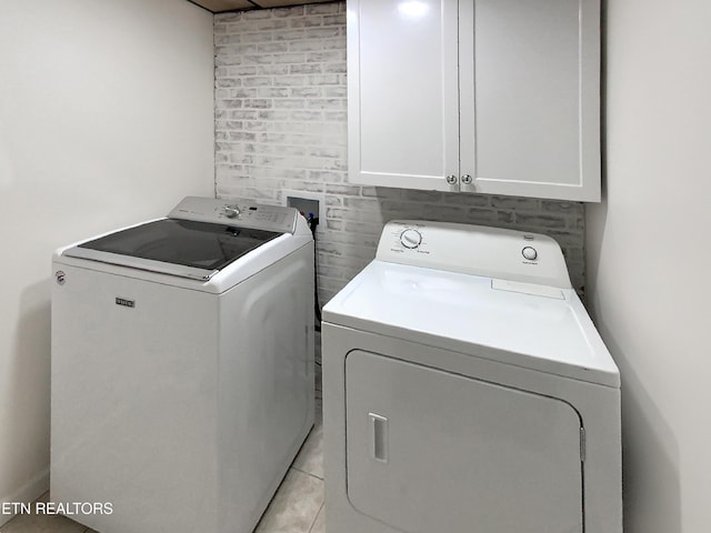 laundry room featuring separate washer and dryer, cabinets, and light tile patterned floors