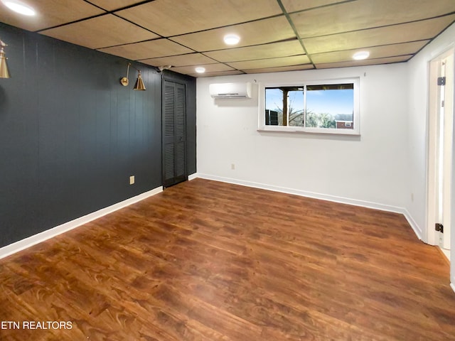 basement with hardwood / wood-style floors, a drop ceiling, and a wall mounted AC