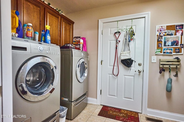 laundry area with cabinets, light tile patterned floors, and washer and dryer