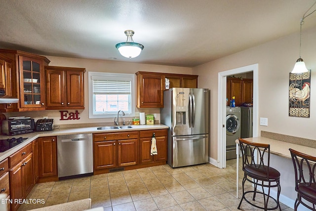 kitchen featuring washer / dryer, decorative light fixtures, stainless steel appliances, sink, and light tile patterned flooring