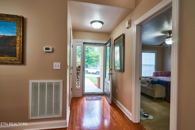 entryway with ceiling fan, a textured ceiling, and hardwood / wood-style floors