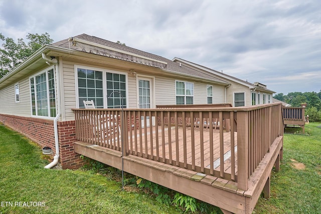 back of house featuring a deck and a lawn