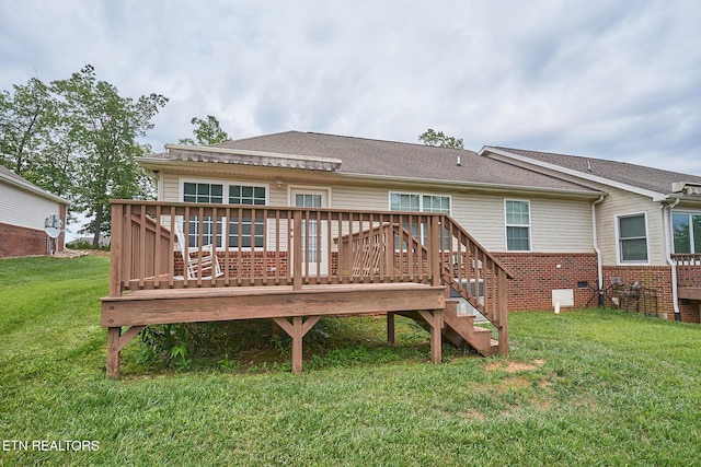 rear view of property with a wooden deck and a lawn