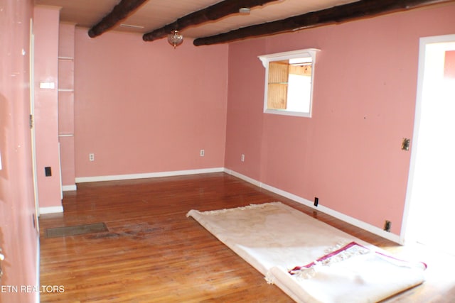 unfurnished room featuring wood-type flooring, wooden ceiling, and beam ceiling