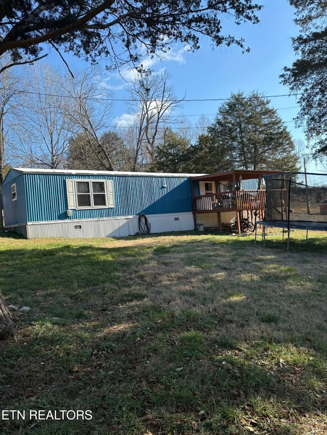 view of front facade with a wooden deck, a front yard, and a trampoline