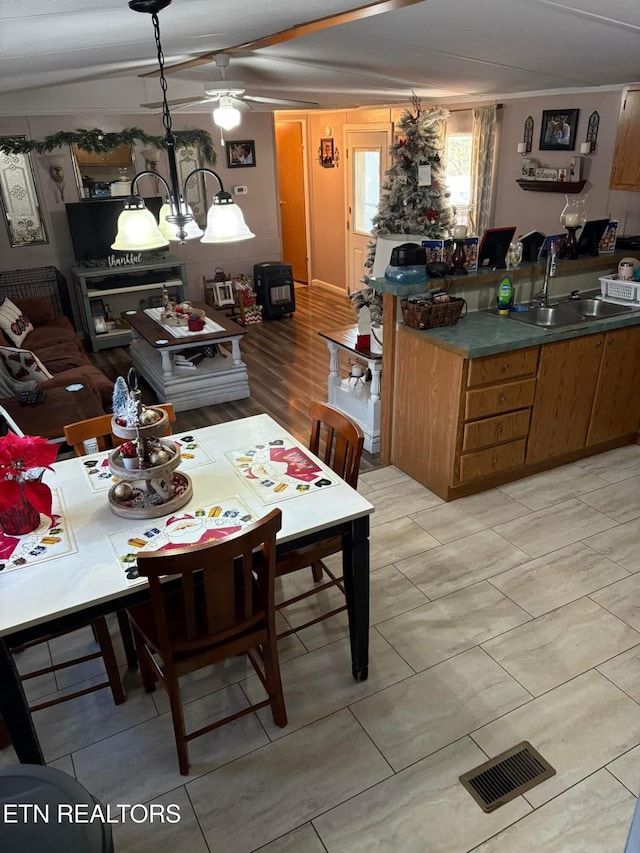 dining area featuring ceiling fan with notable chandelier and sink