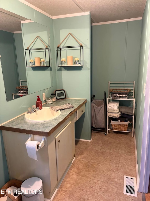 bathroom with a textured ceiling, ornamental molding, and vanity