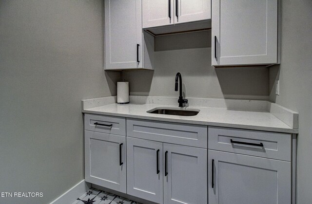 kitchen with light countertops, a sink, and baseboards