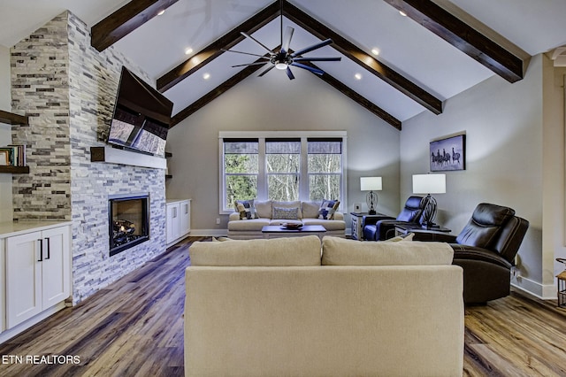 living room with ceiling fan, high vaulted ceiling, a stone fireplace, and wood finished floors