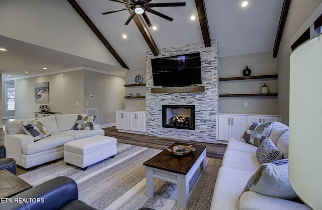 living room featuring dark wood-style flooring, beam ceiling, visible vents, a stone fireplace, and high vaulted ceiling