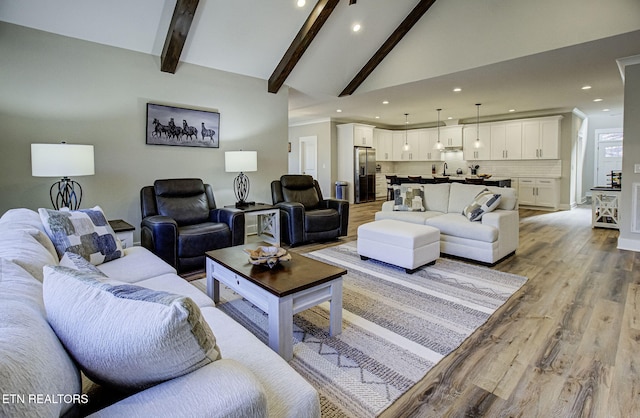 living room with high vaulted ceiling, light wood-style flooring, beam ceiling, and recessed lighting