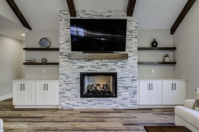 unfurnished living room with vaulted ceiling with beams, a fireplace, baseboards, and wood finished floors