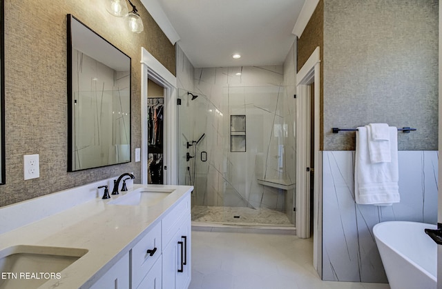 bathroom featuring a freestanding tub, a sink, a marble finish shower, and double vanity