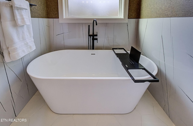 bathroom featuring wainscoting, tile patterned flooring, and a freestanding tub