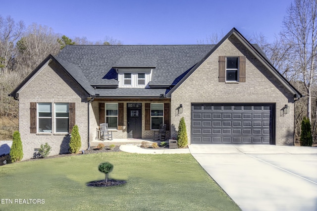 view of front of property with brick siding, a porch, a shingled roof, concrete driveway, and a front yard