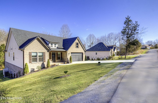 view of front of house featuring brick siding, roof with shingles, concrete driveway, central AC unit, and a front yard