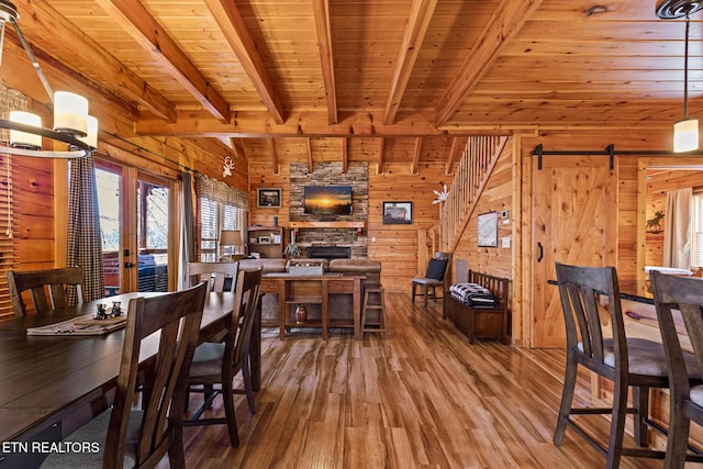 dining room with wood walls, wood ceiling, a barn door, wood-type flooring, and beam ceiling