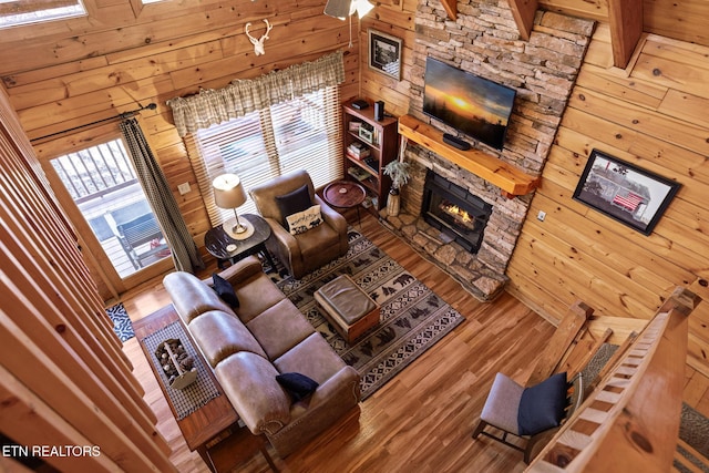 living room featuring wood-type flooring, a fireplace, and wood walls